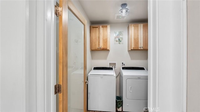 clothes washing area with washer and clothes dryer and cabinets