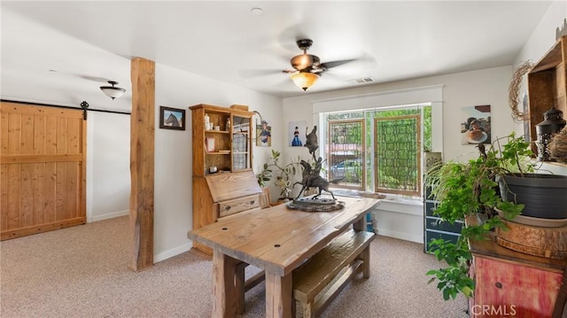 dining area with a barn door, carpet floors, and ceiling fan