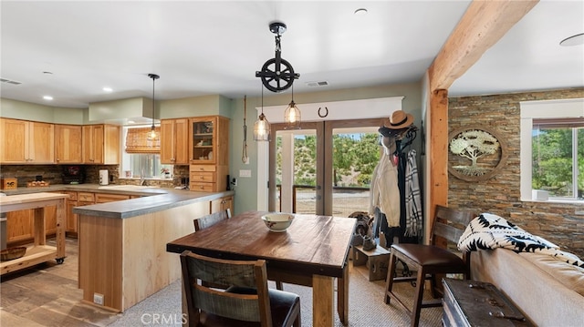 kitchen with french doors, light wood-type flooring, backsplash, stainless steel counters, and pendant lighting