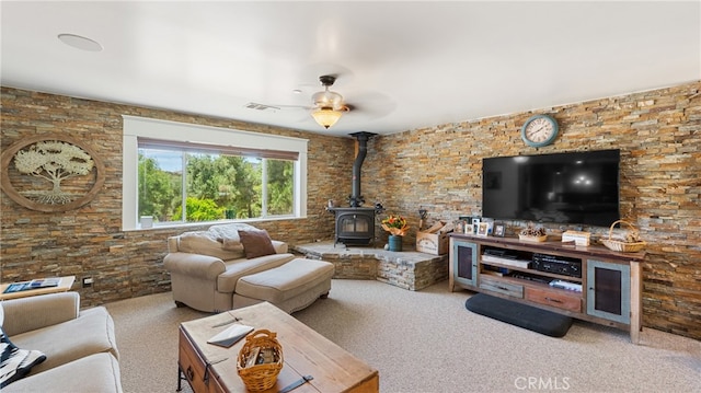 living room featuring light carpet, a wood stove, and ceiling fan