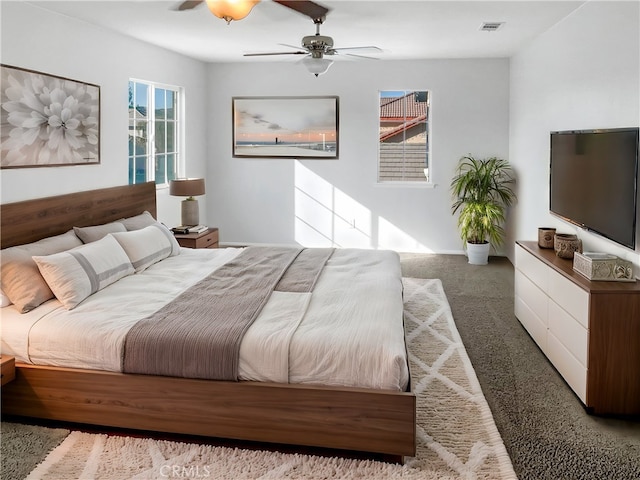 bedroom featuring dark carpet, visible vents, and a ceiling fan