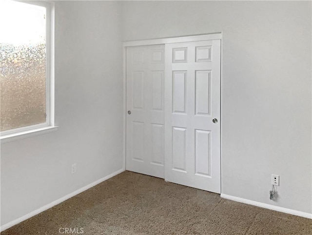 unfurnished bedroom with carpet floors, a closet, and baseboards