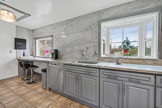 kitchen featuring gray cabinets, sink, light tile patterned flooring, and stainless steel dishwasher