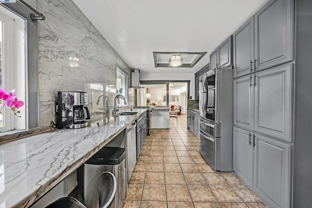 kitchen featuring gray cabinets, sink, light stone countertops, and stainless steel appliances