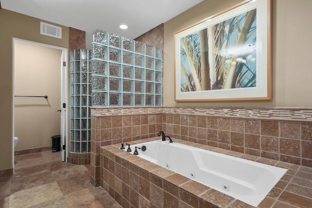 bathroom featuring a relaxing tiled tub and toilet