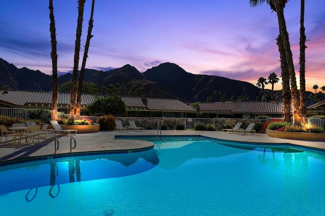 pool at dusk with a mountain view and a patio area