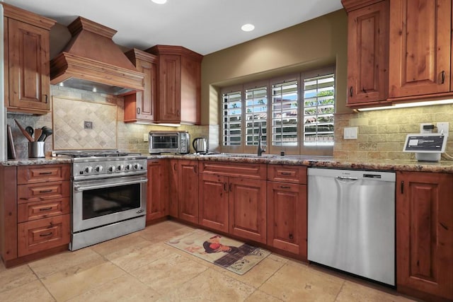 kitchen with light stone counters, premium range hood, appliances with stainless steel finishes, and tasteful backsplash