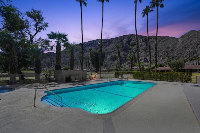 pool at dusk with a mountain view and a patio