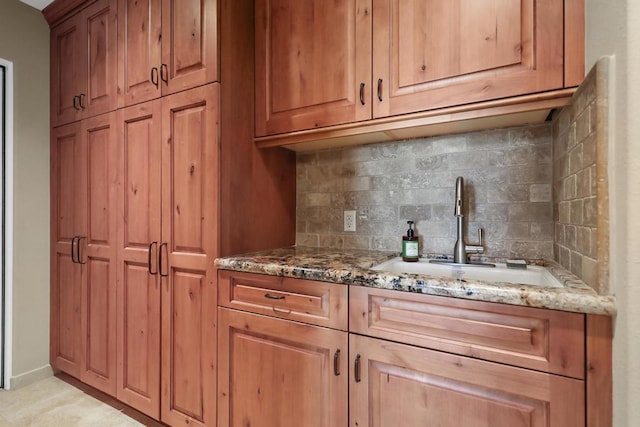 kitchen with backsplash, sink, and stone countertops