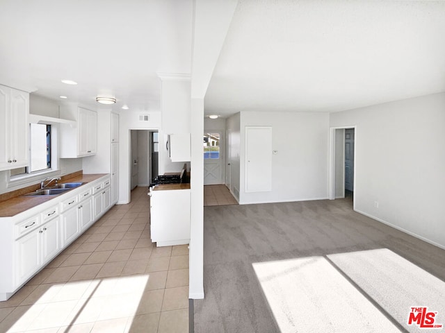 kitchen featuring sink, white cabinetry, light carpet, and a wealth of natural light