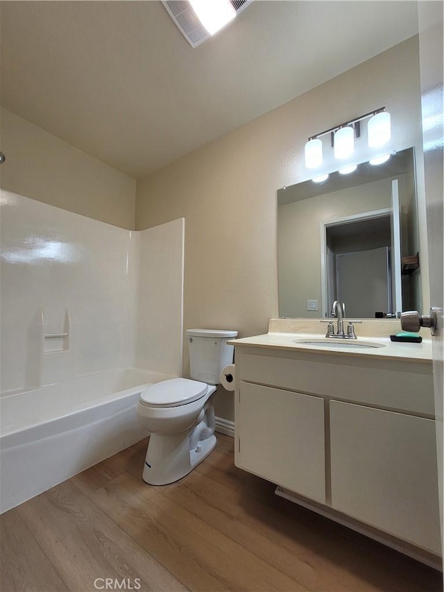 full bathroom with shower / washtub combination, toilet, vanity, and hardwood / wood-style flooring