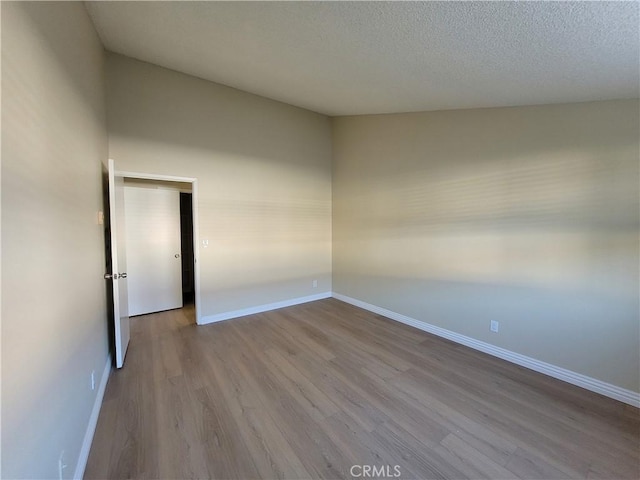 empty room featuring a textured ceiling and light hardwood / wood-style flooring