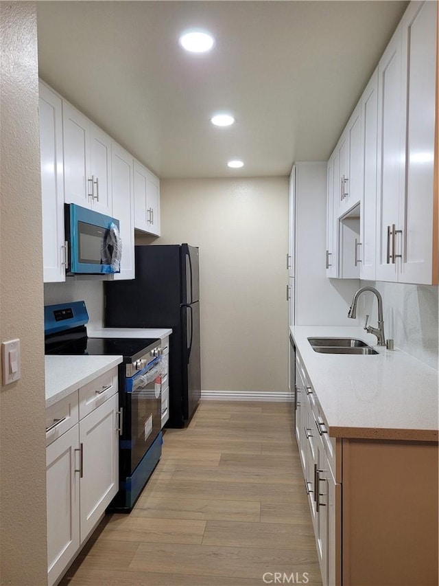 kitchen featuring light hardwood / wood-style floors, white cabinetry, sink, and black range with electric cooktop