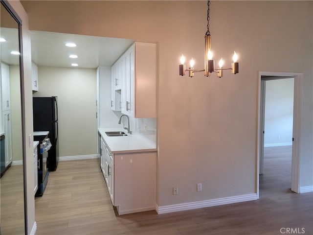 kitchen with white cabinetry, sink, a chandelier, decorative light fixtures, and black appliances