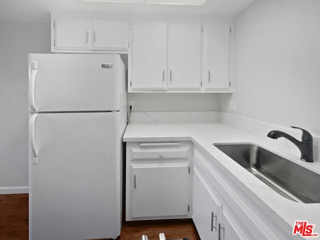 kitchen with white refrigerator, white cabinets, and sink