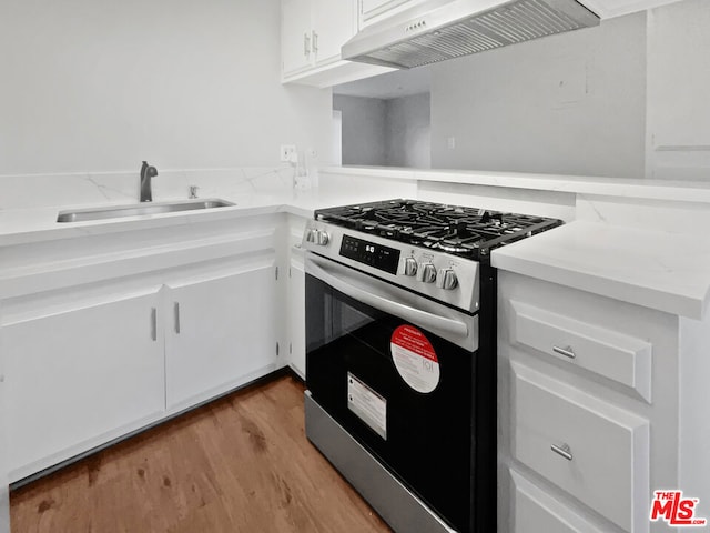 kitchen with sink, white cabinetry, light hardwood / wood-style flooring, custom range hood, and gas range