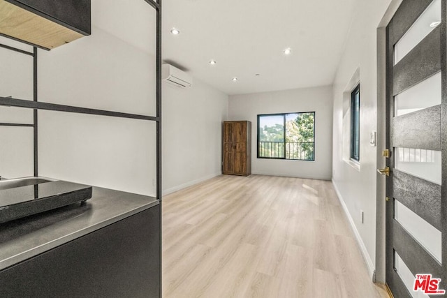 unfurnished living room featuring an AC wall unit and light hardwood / wood-style floors