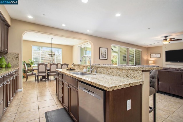 kitchen featuring a kitchen bar, a kitchen island with sink, dishwasher, pendant lighting, and sink