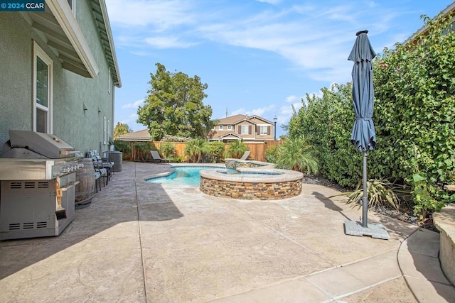 view of patio / terrace featuring a swimming pool with hot tub, an outdoor kitchen, and area for grilling