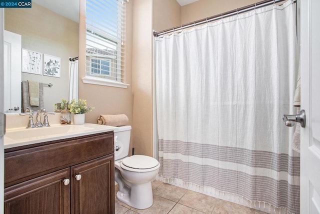 bathroom with toilet, vanity, and tile patterned flooring