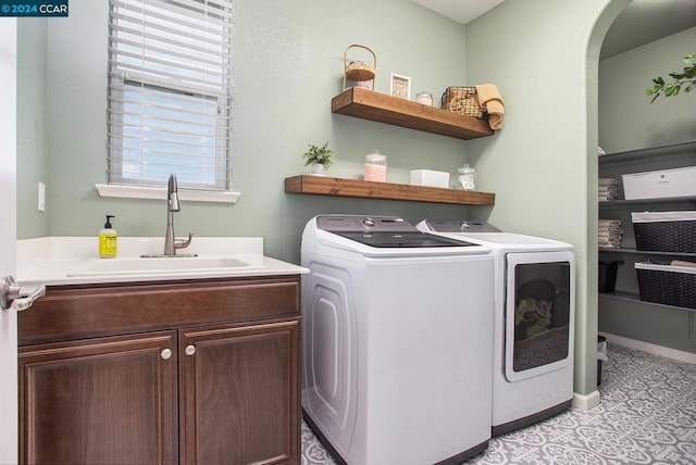 clothes washing area featuring cabinets, sink, light tile patterned floors, and separate washer and dryer