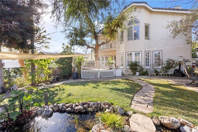 rear view of property featuring a lawn, a patio, and a wooden deck