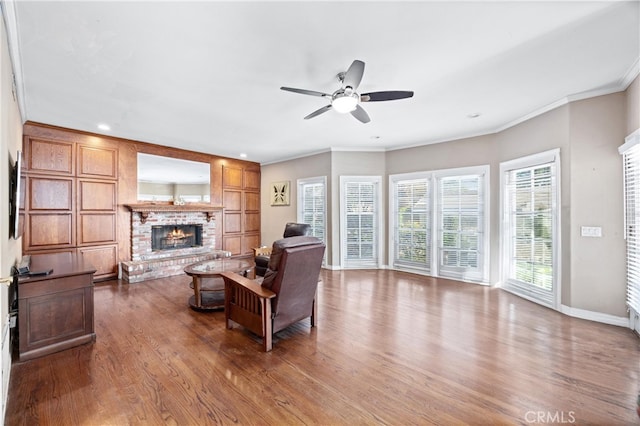 living room with ceiling fan, crown molding, a fireplace, and hardwood / wood-style floors