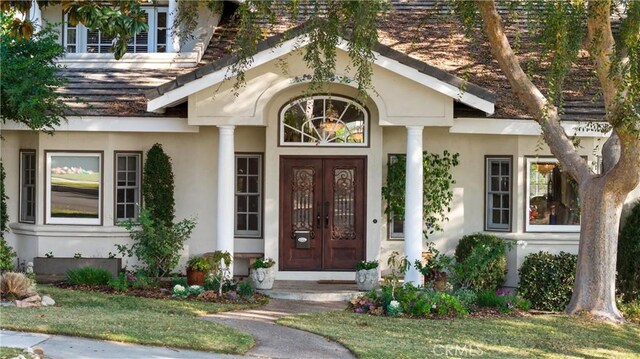 entrance to property with french doors and a lawn