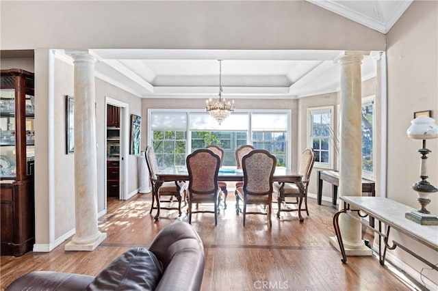 dining room with an inviting chandelier, crown molding, hardwood / wood-style floors, and decorative columns