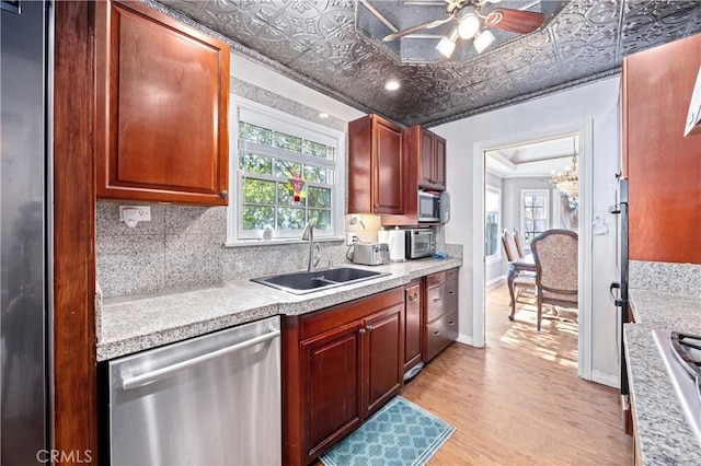 kitchen featuring light wood-type flooring, appliances with stainless steel finishes, sink, and ceiling fan with notable chandelier