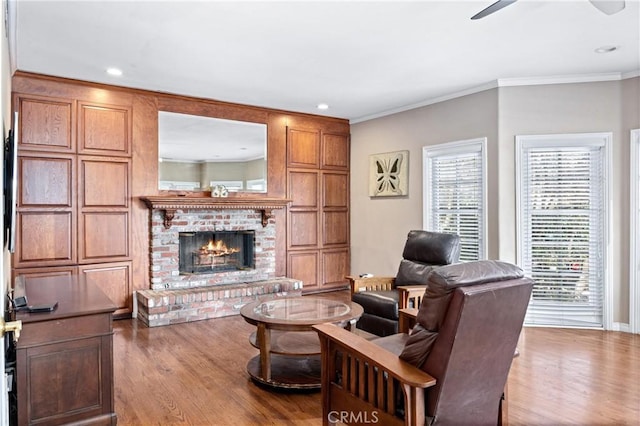 living room featuring ceiling fan, light hardwood / wood-style flooring, ornamental molding, and a fireplace