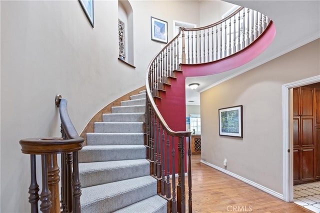 stairs with ornamental molding and hardwood / wood-style flooring