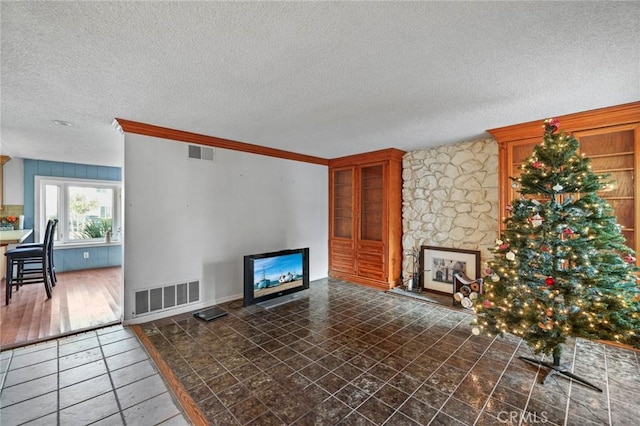 living room featuring a fireplace, ornamental molding, and a textured ceiling