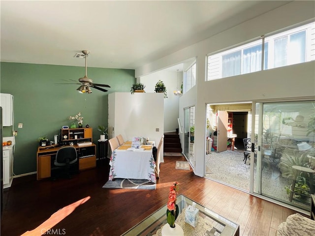 living room featuring a towering ceiling, dark hardwood / wood-style floors, and ceiling fan