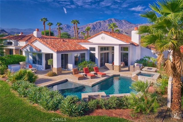 back of house with a patio area, an outdoor living space, a swimming pool with hot tub, and a mountain view