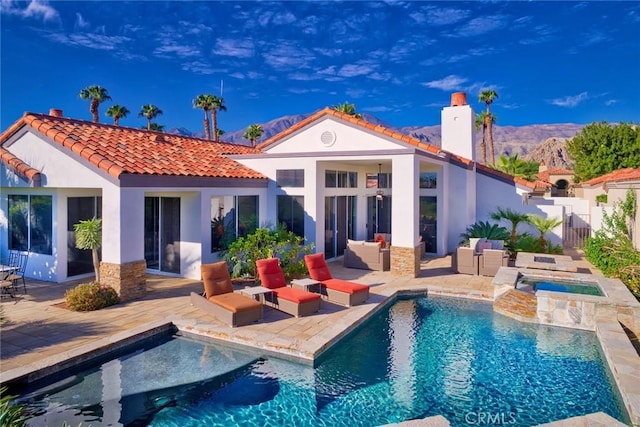 back of house with a mountain view, a swimming pool with hot tub, a patio, and an outdoor hangout area