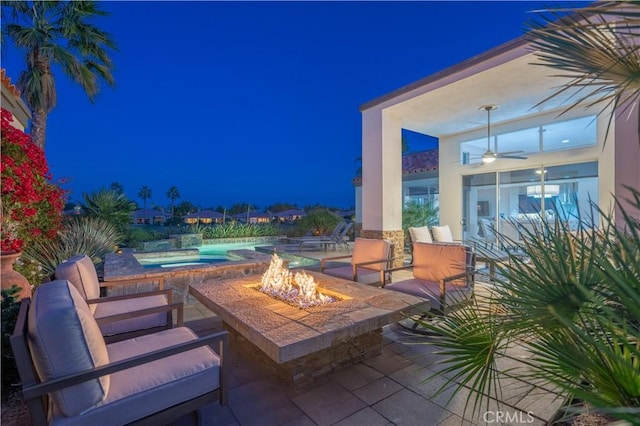 patio at night with ceiling fan and an outdoor fire pit