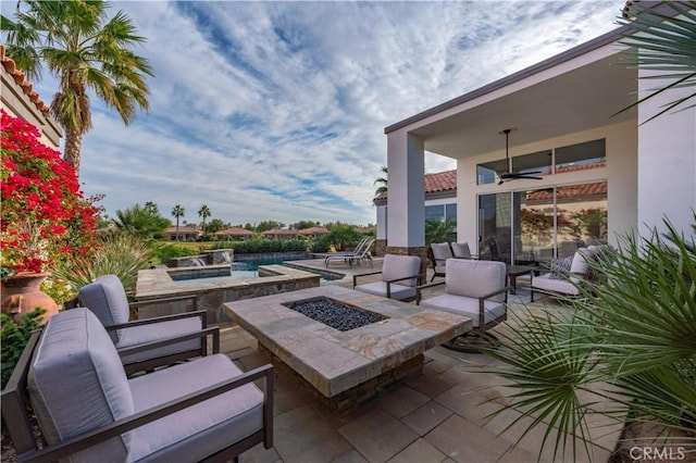 view of patio / terrace featuring ceiling fan and an outdoor living space with a fire pit