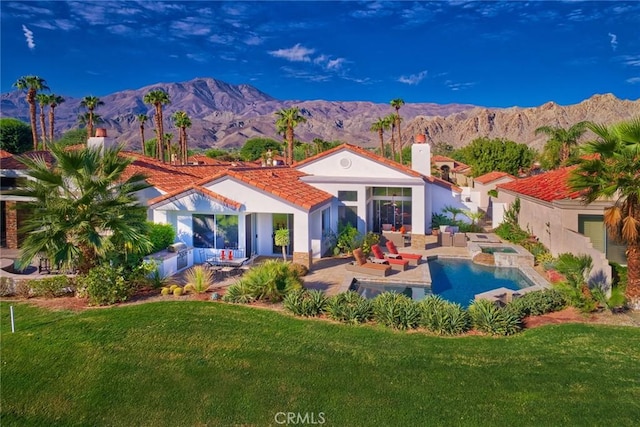 rear view of property with a mountain view, a yard, a patio, and an outdoor hangout area