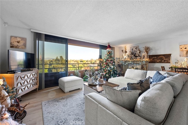 living room featuring a textured ceiling, light hardwood / wood-style flooring, and a wall of windows