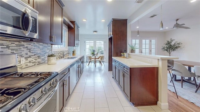 kitchen with appliances with stainless steel finishes, french doors, tasteful backsplash, ceiling fan, and hanging light fixtures