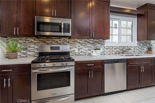 kitchen with sink, decorative backsplash, light tile patterned floors, dark brown cabinets, and stainless steel appliances