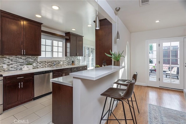 kitchen with a breakfast bar, hanging light fixtures, stainless steel dishwasher, tasteful backsplash, and a kitchen island