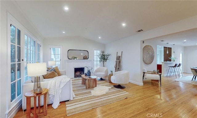 living room featuring light hardwood / wood-style floors, lofted ceiling, and a healthy amount of sunlight