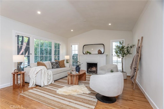 living room featuring light hardwood / wood-style floors, lofted ceiling, and ornamental molding