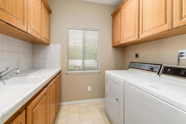 clothes washing area with cabinets, separate washer and dryer, and sink