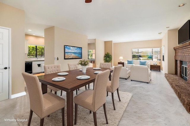 dining area featuring light colored carpet, a fireplace, and a wealth of natural light