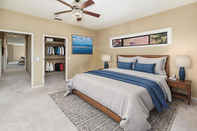 bedroom featuring ceiling fan, light carpet, a closet, and a walk in closet