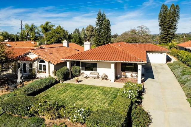 mediterranean / spanish house featuring a front lawn, a patio area, and a garage