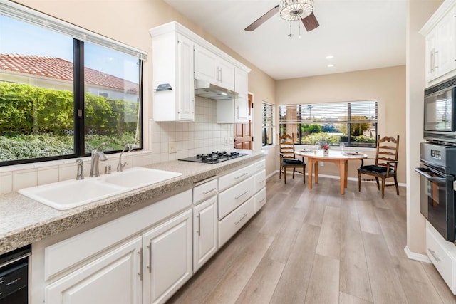 kitchen featuring sink, white cabinetry, black appliances, and tasteful backsplash